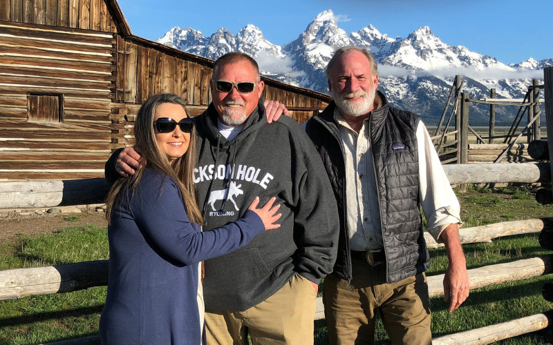 Tour Guide posing with tourists in front Teton Mountains